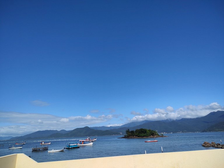 Beira-mar, piscina e vista montanha com pôr do sol